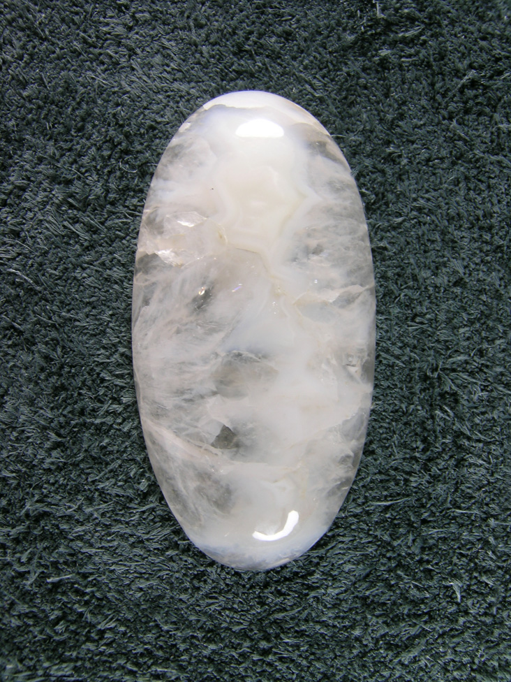 Horse Canyon Agate 707  :  A Milky floater in a Solid Crystal Quartz cab.  Cut thinned I am sure this would have Iris'd