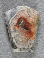 Crazy Lace Agate 697  :  A bola shape in White fortification around an intricate center and Iron staining.